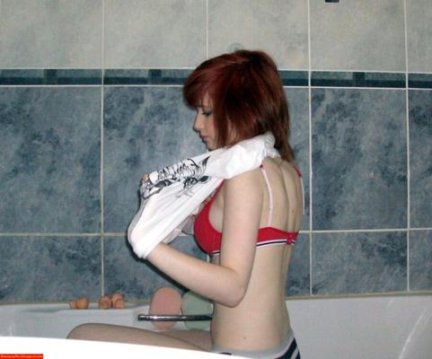 Jeune rousse maigre avec de beaux seins en train de tirer dans la salle de bain